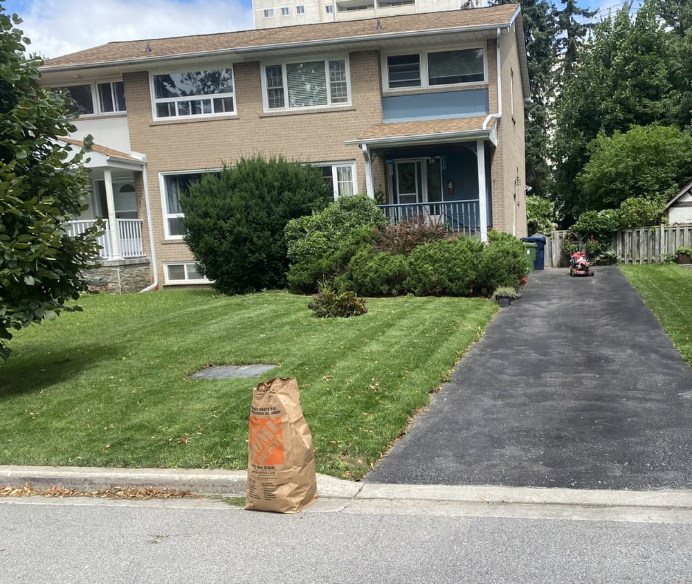 A mowed front lawn with yard waste bagged at the curb